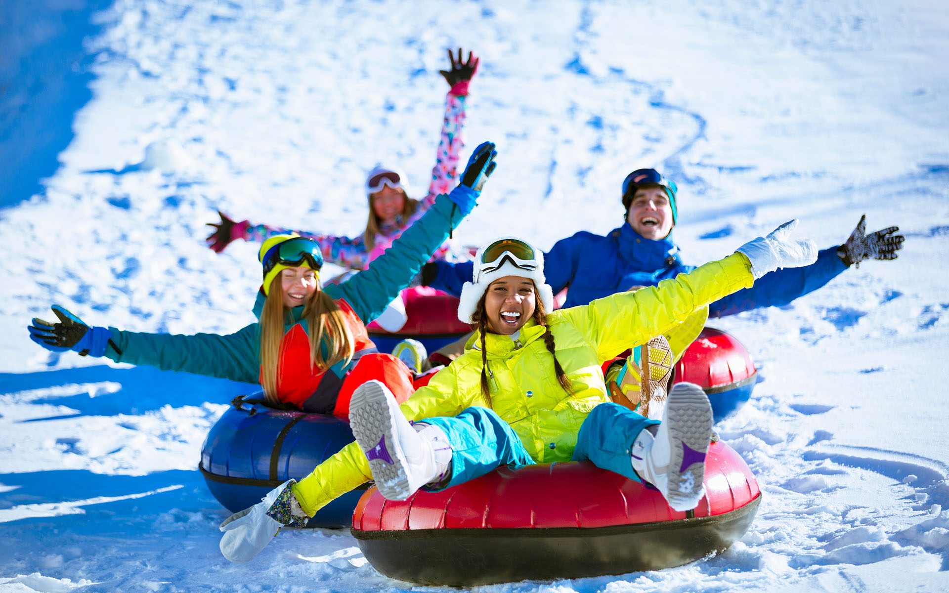 Winter Staycation - Group of People Tubing Down a Snowy Hill